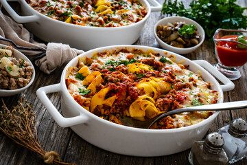 Noodle casserole with minced meat, mozzarella cheese and vegetables on wooden table
