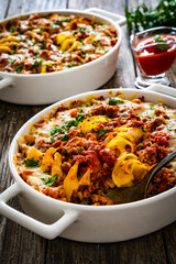 Noodle casserole with minced meat, mozzarella cheese and vegetables on wooden table
