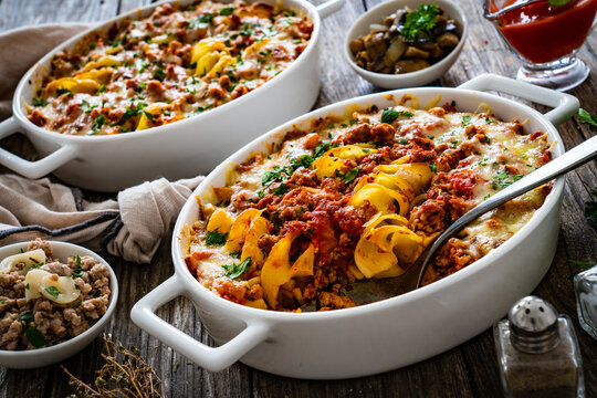 Noodle casserole with minced meat, mozzarella cheese and vegetables on wooden table
