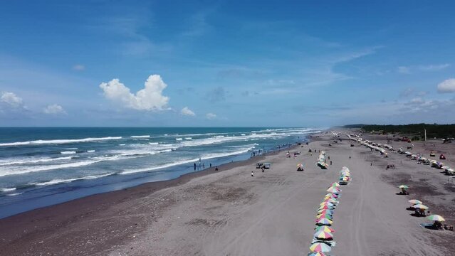 Aerial view of a beautiful tropical beach with blue sky, waves and white clouds in the background. Parangtritis Beach, Indonesia