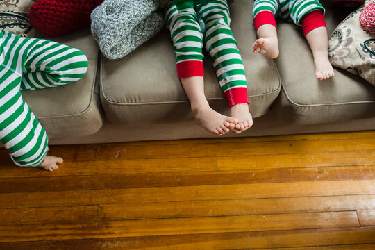 Legs and feet of children sitting on sofa during Christmas celebration