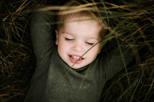Little cute boy is lying on the green grass on a sunny day