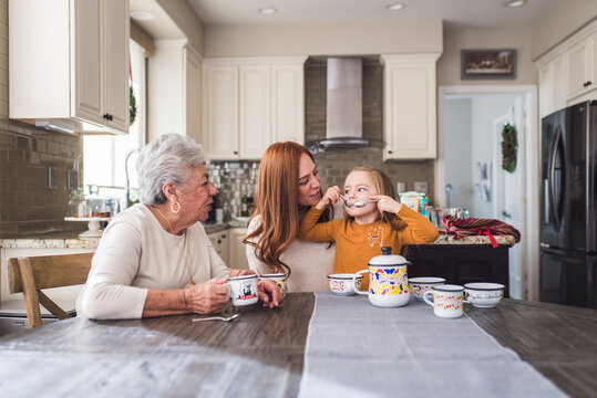 Multigenerational family playing with tea set at kitchen table