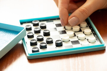 Board small old game checkers on the table and woman's hand close-up, board games