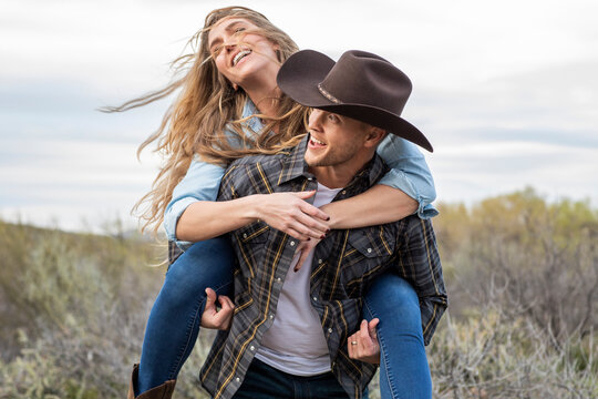Western wear young couple enjoying piggy back ride on ranch