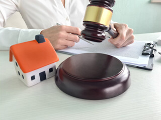 Judge is holding wooden gavel near toy house closeup