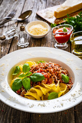 Fusilli with minced meat, tomato sauce, parmesan cheese and basil served on wooden table
