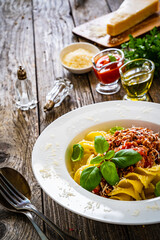 Fusilli with minced meat, tomato sauce, parmesan cheese and basil served on wooden table
