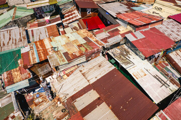 Manila, Philippines - Mar 2023: Closeup above view of cramped shanty houses with roofs made of rusted sheet metal at a slum area.