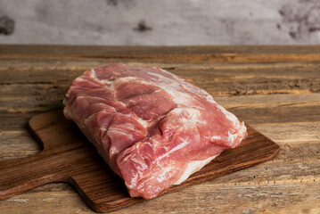 Piece of pork loin on a cutting board,on an old wooden table,close-up.