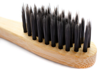 Wooden bamboo toothbrush with black bristles isolated on white background, close-up. Bamboo wood toothbrush with black bristles isolated on white, macro. Natural environmentally friendly zero waste.