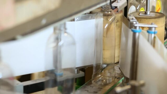 A closeup of plastic bottles being labelled by a labelling machine