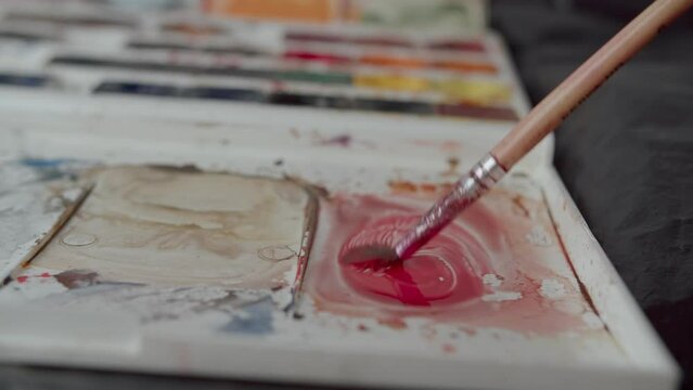 mixing burgundy paint on watercolor paint palette