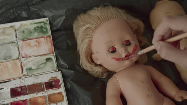 man paints a smile on the doll's face