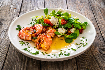 Fried prawns with tomatoes and greens wooden table
