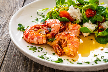 Fried prawns with tomatoes and greens wooden table
