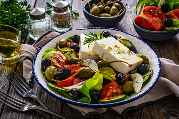 Fresh vegetable salad with feta cheese on wooden table
