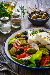 Fresh vegetable salad with feta cheese on wooden table
