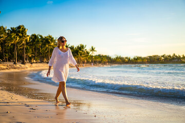 Beach holiday - beautiful woman walking on sunny, tropical beach 
