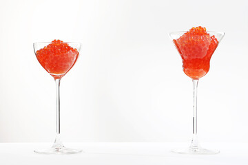 Red salmon caviar.Red caviar in tall glass wine glasses. White background. Isolated object. Copy space.