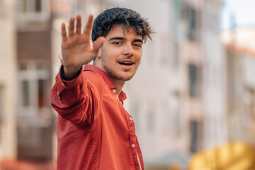 young man on the street waving his hand