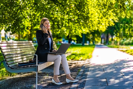 Beautiful woman talking on the phone sitting on bench in park