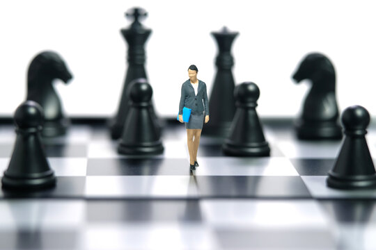 Miniature people toy figure photography. A businesswoman walking above chessboard in the middle of chess piece. Isolated on white background