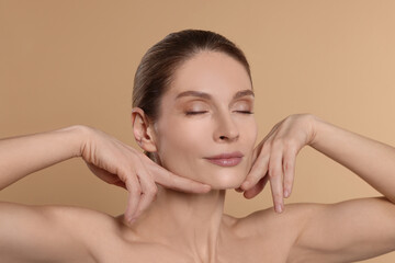 Naklejka premium Woman massaging her face on beige background