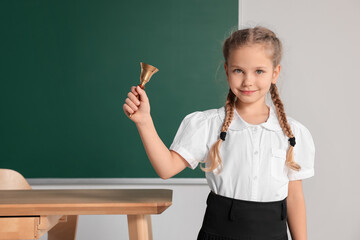 Pupil with school bell near chalkboard in classroom, space for text