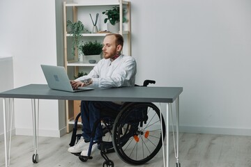 A man in a wheelchair a businessman with tattoos in the office works at a laptop, integration into...