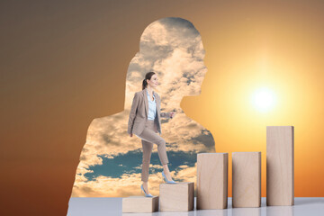 Thinking about steps to success. Businesswoman climbing up stairs of wooden blocks inside of...