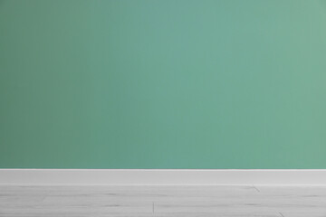 Beautiful light green wall and wooden floor in clean empty room