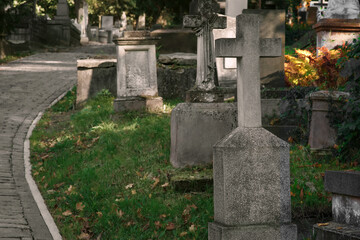 Fototapeta premium View of cemetery with granite tombstones and paved footpath on sunny day. Funeral ceremony