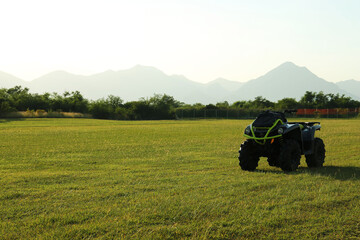 Obraz premium Modern quad bike in field on sunny day, space for text
