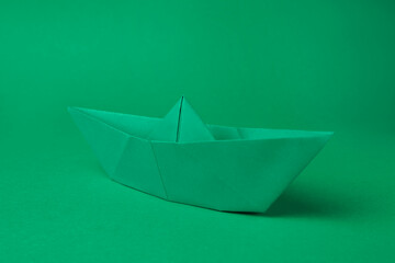 Origami art. Paper boat on green background