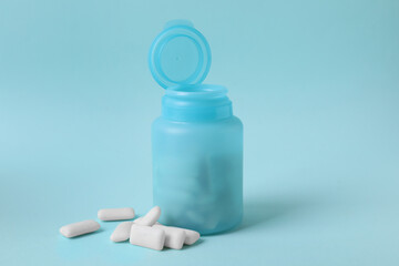 Color jar with chewing gums on light blue background