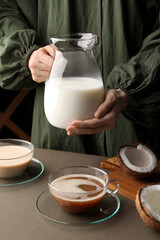 Woman with jug of tasty coconut milk at table, closeup