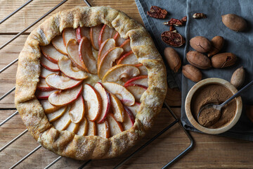 Delicious apple galette, cinnamon and pecans on wooden table, flat lay