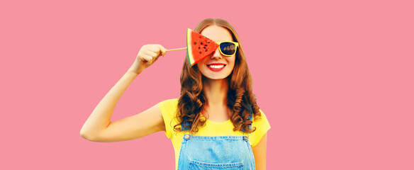 Summer portrait of happy smiling young woman with fresh juicy fruits, lollipop or ice cream shaped slice of watermelon on pink background