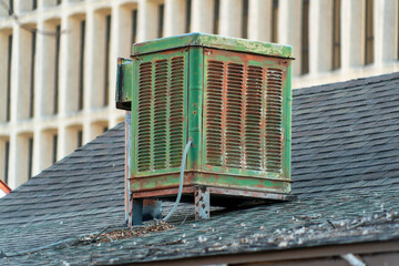 Swamp cooler air condition system on rooftop in modern city with green color and aged and weathered metal body