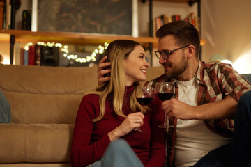 Romantic young couple relaxing at home and drinking red wine