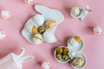 Fototapeta na wymiar Golden glitter Easter eggs on plate in shape of rabbit on pink background