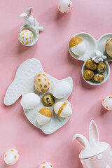 Golden glitter Easter eggs on plate in shape of rabbit on pink background