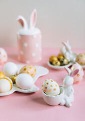 Golden glitter Easter eggs on plate in shape of rabbit on pink background