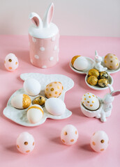Golden glitter Easter eggs on plate in shape of rabbit on pink background