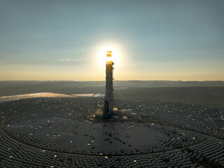 Hydroelectric Solar tower power station at sunrise in a desert landscape