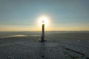 Hydroelectric Solar tower power station at sunrise in a desert landscape