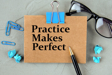 PRACTICE MAKES PERFECT - words on brown paper on the background of glasses, pens and paper clips