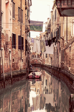 Old narrow canal in Venice with old houses and laundry hanging on a rope (vintage style photo)