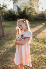 Girl with white hair in sunset light. Children's smart watch.